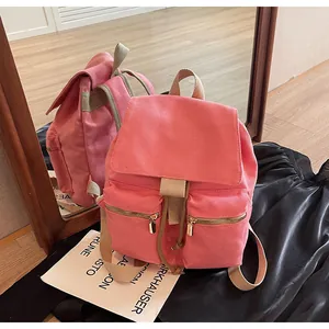 Detalle de mochila de lona rosa con cierre de cordón y bolsillos con cremallera dorada