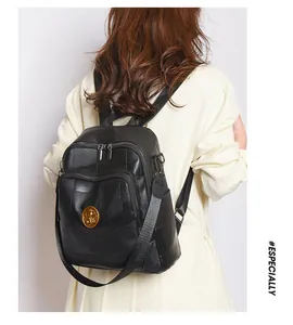 Detail of black patchwork leather backpack showing adjustable straps and gold emblem