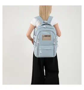 Detail view of light blue multi-pocket backpack showing zip pockets and fashion patch