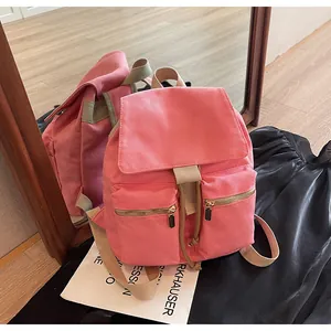 Primer plano de mochila de lona rosa con cierre de cordón y cremalleras doradas