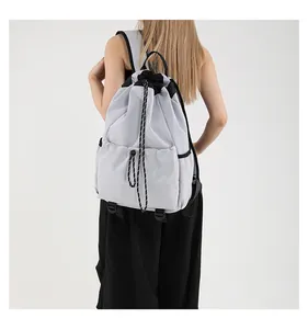 Vue arrière d'un sac à dos en nylon gris clair avec cordons noirs porté par un mannequin