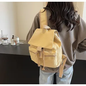Mochila vintage de lona amarilla llevada por una modelo en un café acogedor