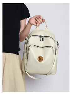 Detail of creamy white faux leather backpack featuring crocodile texture and bear logo