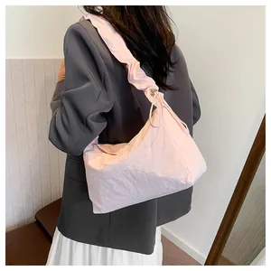 Detail der hellrosa plissierten Canvas-Schultertasche mit gerafftem Kordelzug am Model