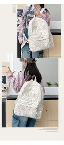 Détail du sac à dos en toile fleurie avec poche avant zippée et tirettes en corde blanche