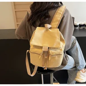 Vista detallada de una mochila de lona amarillo pálido con cordón y dos bolsillos frontales