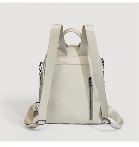 Detail showing the anti-theft zipper pocket and geometric stitching on the cream backpack