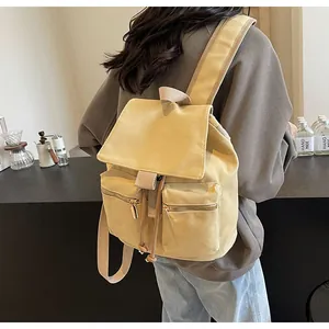 Detalle de una mochila de lona caqui con cordón ajustable y bolsillos delanteros