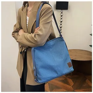 Detail showing blue denim canvas shoulder bag with brown leather patch and woven strap