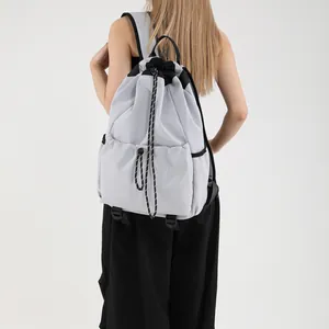 Sac à dos seau en nylon gris clair avec cordon de serrage porté par un mannequin
