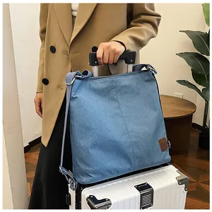 Close-up of blue canvas tote bag with back luggage strap sleeve on a white suitcase handle