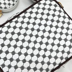 Detail of white cross-body bag with geometric heart pattern and round coin purse attachment