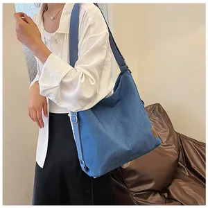Close-up of blue denim hobo bag with brown leather patch and woven crossbody strap