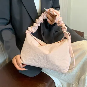 Rosafarbene Canvas-Schultertasche mit gerafftem Griff und Perle auf grauem Hintergrund