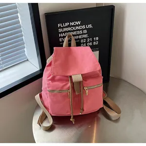 Vista detallada de la mochila de lona rosa con cierre de cordón y bolsillos con cremallera