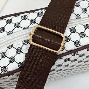 Detail of white leather shoulder bag featuring black clover pattern and brown strap