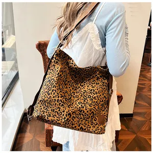 Detail view of the wide woven strap and silver metal buckle on leopard print canvas bag