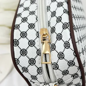 Detail of white lychee leather texture with black clover print and golden zipper slider