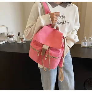 Detalle de mochila tipo cubo de lona rosa con cremalleras dobles y correas en modelo