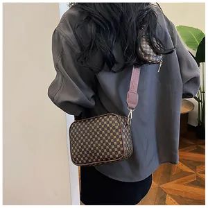 Detail view of vintage brown patterned crossbody bag with wide strap and mini pouch