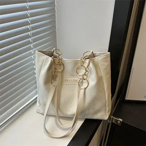 Minimalistische crèmewitte schoudertas met gouden ketting en fashion label in de vensterbank