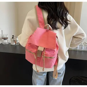Detalle de mochila de lona rosa con cierre de cordón y bolsillos con cremallera de metal