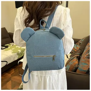 Detail of blue denim backpack with bear ears on a model wearing a white dress
