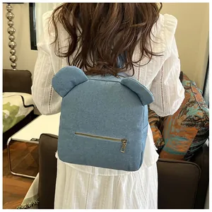Detail of light blue denim backpack with cute bear ears and metallic back zipper