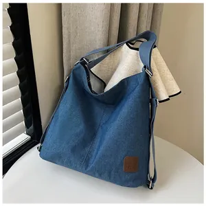 Detailed macro view of blue denim fabric texture and brown leather patch on tote bag
