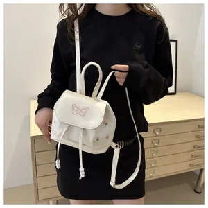 Dettaglio mini zaino in pelle PU bianca con ricamo a farfalla rosa e decoro floreale