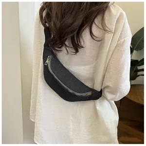 Detail of a black canvas crescent crossbody bag with silver zipper on a model