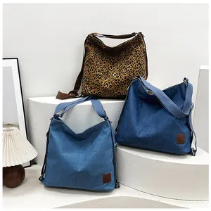 Detail view of large leopard print canvas bags and denim shoulder bags on a display stand