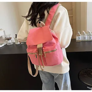 Detalle de mochila de lona rosa con cierre de cordón y dos bolsillos frontales con cremallera
