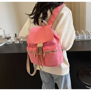Detalle de mochila tipo cubo de lona rosa con cordón y bolsillos con cremallera metálica