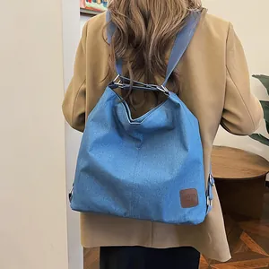 Blue canvas large shoulder bag with wide strap worn with a camel blazer and black pants
