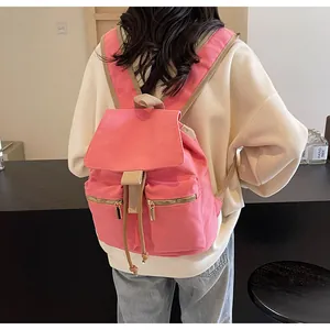 Detalle de la mochila de lona rosa con bolsillos dobles de cremallera y cordón
