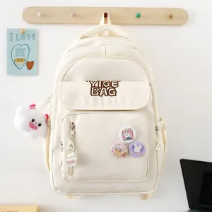 Minimalist beige nylon school backpack with cute plush pendants and cartoon pins for students