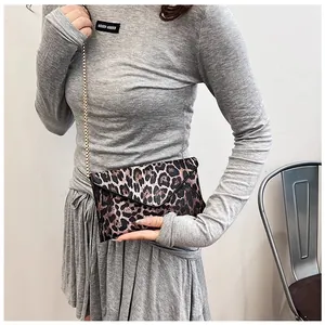 Close-up of leopard print envelope clutch bag with golden chain strap and PU leather texture