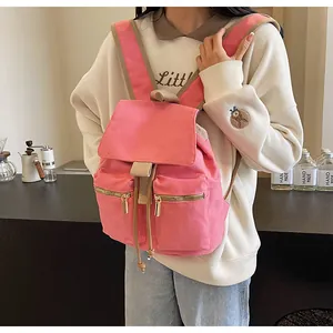 Detalle de mochila de lona rosa con bolsillos frontales dobles y cierre de cordón