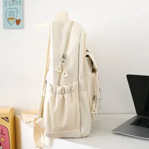 Detail view of the side elastic pocket and unique triangle zipper on the cream backpack