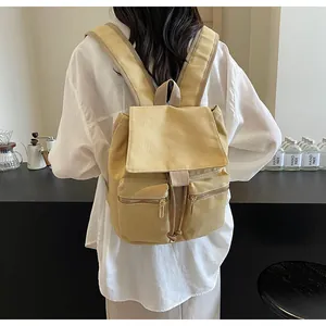 Vista detallada de la mochila de lona caqui en modelo mostrando textura duradera y bolsillos