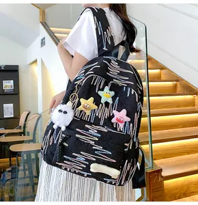 Detail of black quilted backpack with wave embroidery and colorful plush star pendants