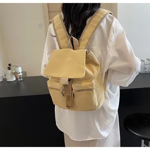 Detalle de mochila de lona mostaza con cordón de ajuste y cremalleras frontales dobles