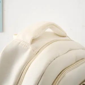 Detail of cream backpack showing thick padded handle and breathable mesh texture