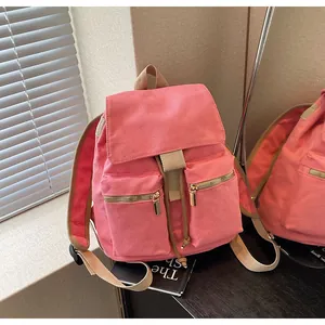 Detalle de la mochila tipo cubo de lona rosa con cierre de cordón y bolsillos de cremallera