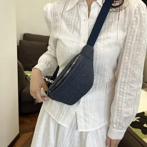 Navy denim chest bag with gold zippers and adjustable strap shown on a model