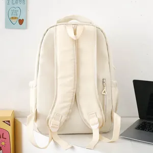 Detailed back view of cream nylon backpack featuring padded straps and anti-theft zipper