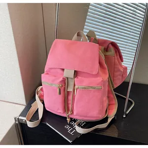 Vista detallada de mochila de lona rosa con cierre de cordón y bolsillos de cremallera