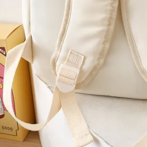 Detail of reinforced shoulder strap stitching and white plastic buckle on nylon backpack