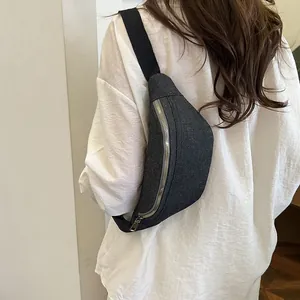 Minimalist black canvas chest bag with silver zipper shown on a white shirt model